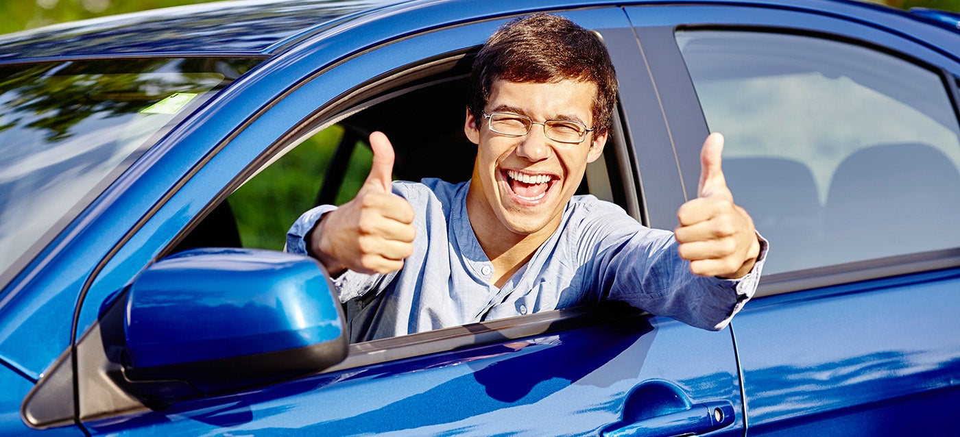 college student in a car holding 2 thumbs up